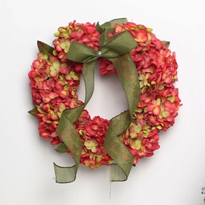 Détail d'une couronne d'hortensias artificiels rose-rouge avec un nœud en toile