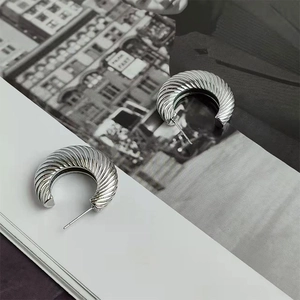 Macro shot of silver-tone textured spiral hoop earrings on a fashion magazine page