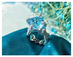 Macro shot of Asscher cut blue gemstone ring with pave diamond setting on blue silk