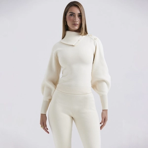 Detail of cream knit set featuring high neck asymmetric button top and ribbed lantern sleeves