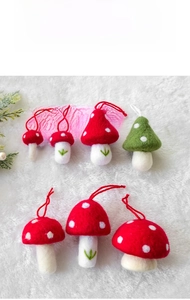 Detailed view of handmade wool felt mushroom ornaments on white faux fur background