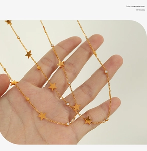 Detail of gold star necklace with zircon stones held in hand for quality check