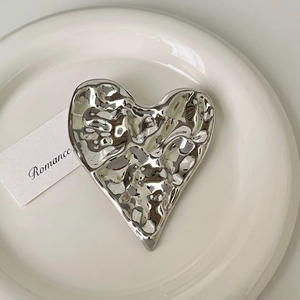 Detailed view of silver irregular heart brooch with hammered liquid metal texture