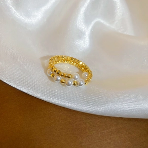 Close-up of double-layered beaded ring with gold faceted beads and white pearls on silk