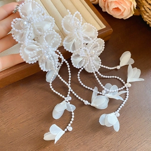 Detail of white chiffon petal tassel clip earrings with elegant faux pearl embellishments