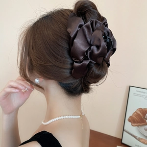 Detail view of large dark coffee satin cloud hair claw clip worn by a model in a bun style