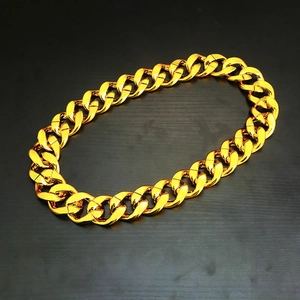 Macro-opname van een dikke gouden Cubaanse ketting met gepolijste afwerking op houten blad
