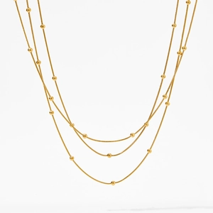 Gros plan d'un collier de perles dorées à plusieurs rangs aux sphères polies lisses
