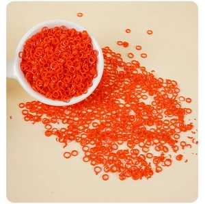 Detailed view of mini orange PVC chili rings scattered from a white ceramic spoon