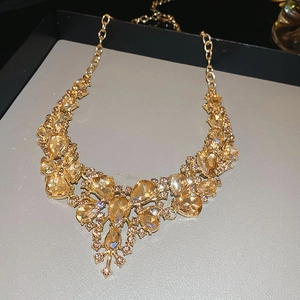 Macro shot of gold drop necklace featuring sparkling champagne crystals and ornate stones