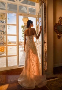 Detailed view of white off-shoulder bridal gown with intricate lace and corset tie back