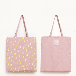 Detail of pink canvas tote bags with abstract geometric prints and motivational text labels