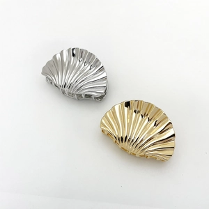 Detail of polished gold and silver shell-shaped metal hair claws with ribbed texture