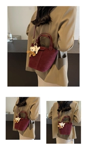 Detail der burgunderroten Bucket Bag aus Wildleder mit Bärenanhänger und Schultergurt