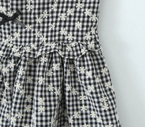 Close-up of black and white plaid dress with floral embroidery and black ribbon bow detail