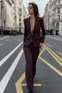 Photo street style d'une femme en blazer bordeaux à col en V et pantalon droit assorti