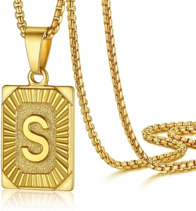 Close-up of golden rectangular pendant with engraved letter S on a box chain