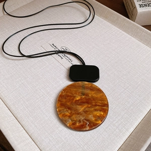 Detail of geometric resin pendant featuring amber texture and black long cord necklace