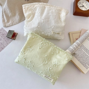 Detail of floral lace embroidery and fabric texture on a handheld makeup bag