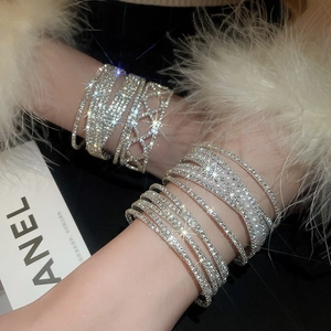 Close-up of sparkling multilayer pearl and diamond bracelets on model with feather detail