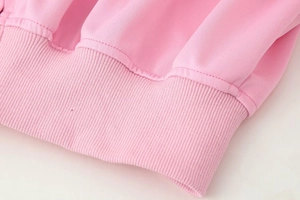 Macro detail of pink ribbed knit hem with elastic double-needle stitching on jacket