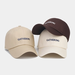 Détail de trois casquettes en coton en kaki, beige et café avec broderie de lettres