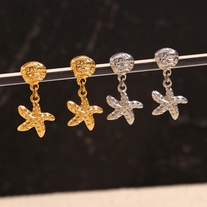 18K gold and silver starfish earrings set hanging on a minimalist display stand