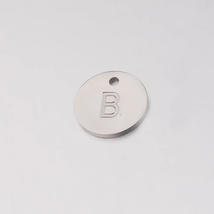 Detailed macro view of a round silver stainless steel charm with an engraved letter B