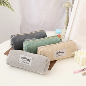 Corduroy shark pencil cases in grey, green and khaki on a desk with art supplies