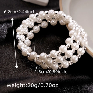 Detail view of multi-layer pearl and rhinestone spiral bracelet on dark silk background