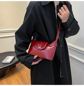 Close-up of red glossy patent leather crossbody bag with elegant gold metallic buckle