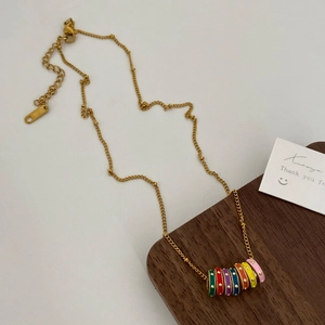 Close-up of gold chain necklace with seven colorful enamel beads on wooden display