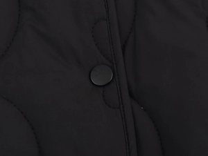 Gros plan d'une veste matelassée noire montrant la texture du tissu et le bouton rond