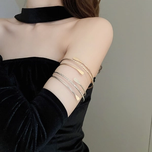 Detail of layered gold and silver open arm cuffs with elegant teardrop shaped ends