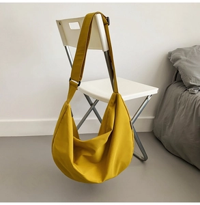 Detailed view of large bright yellow oxford fabric crossbody bag on a white chair