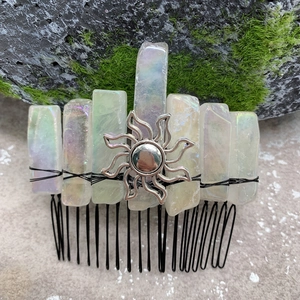 Detail of handmade crystal hair comb with rainbow quartz and silver sun on mossy rock