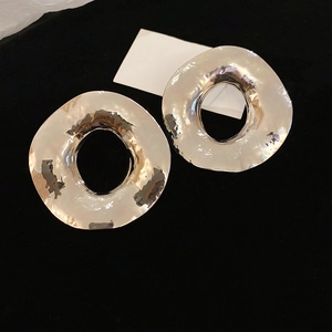 Détail de boucles d'oreilles rondes évidées argentées avec une texture métallique