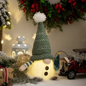 Close-up of a glowing Christmas gnome plush with a green knit hat and small pine tree