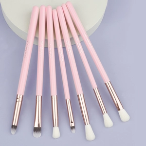 Macro shot of 7 pink professional eye makeup brushes with rose gold ferrules on a platform