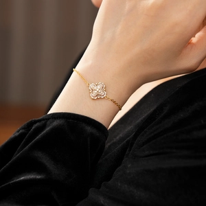 Gros plan d'un bracelet trèfle doré orné de perles et de cristaux scintillants