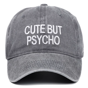Close-up of CUTE BUT PSYCHO white embroidery on washed grey cotton baseball cap