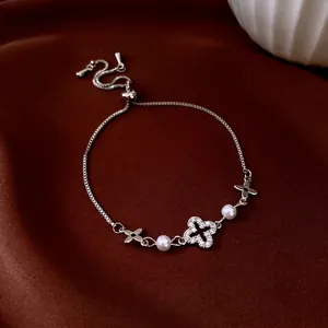 Adjustable silver bracelet with cubic zirconia clover, pearls, and hollow floral charms