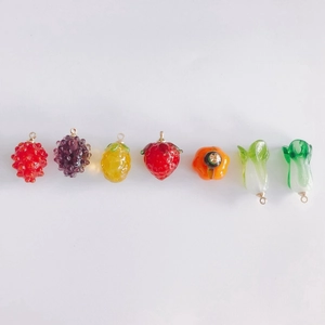 Macro detail of assorted glass fruit and vegetable charms with golden loops