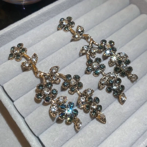 Detail of flower tassel drop earrings with green and white rhinestones in a jewelry box
