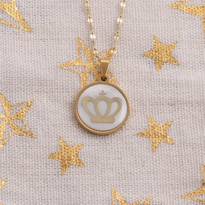 Macro detail of gold crown emblem on white shell pendant with stainless steel chain