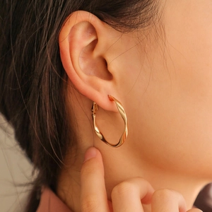 Close-up of elegant gold twisted hoop earrings with polished finish on a model