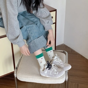 Mid-cut crew socks in cream with green ribbed cuffs and grey heart pattern accents