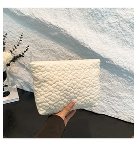 Detail of cream white pleated floral quilted handbag with textured 3D flower pattern