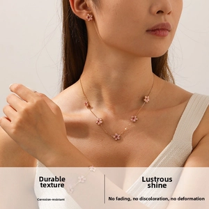 Detail of pink cherry blossom necklace and bracelet set on model with rose gold finish