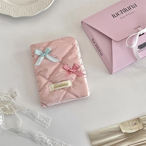 Detailed view of pink quilted passport holder with blue bows and Suzakka logo tag